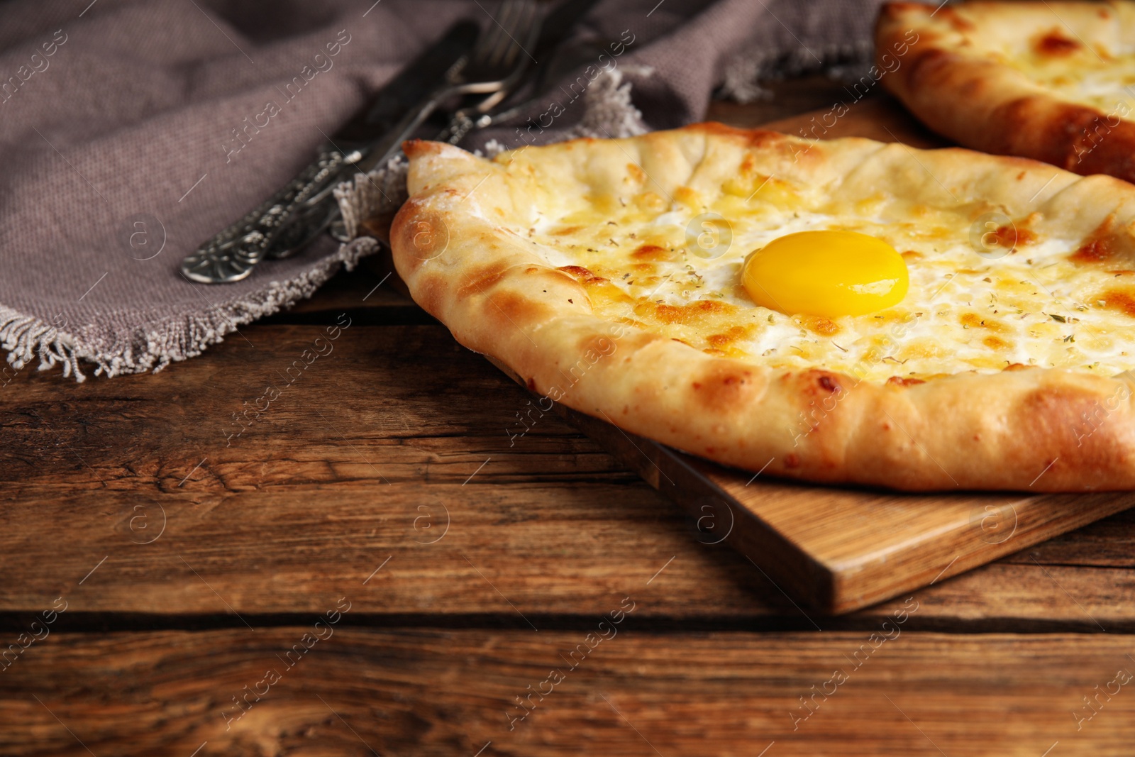 Photo of Fresh homemade khachapuri with cheese and egg on wooden table. Space for text