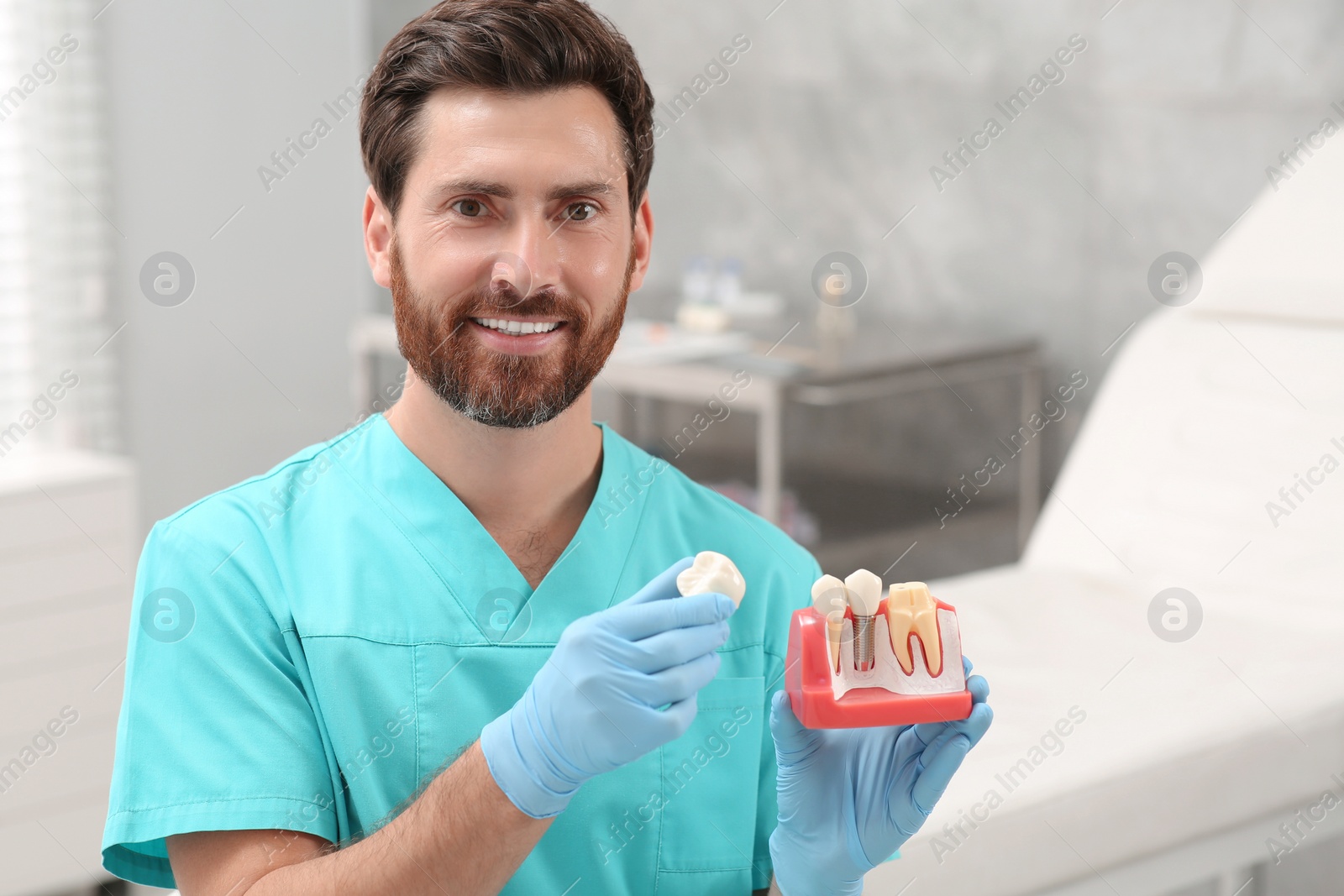 Photo of Dentist holding educational model of dental implant in clinic