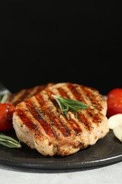 Photo of Delicious grilled pork steaks with spices on table against black background, closeup. Space for text
