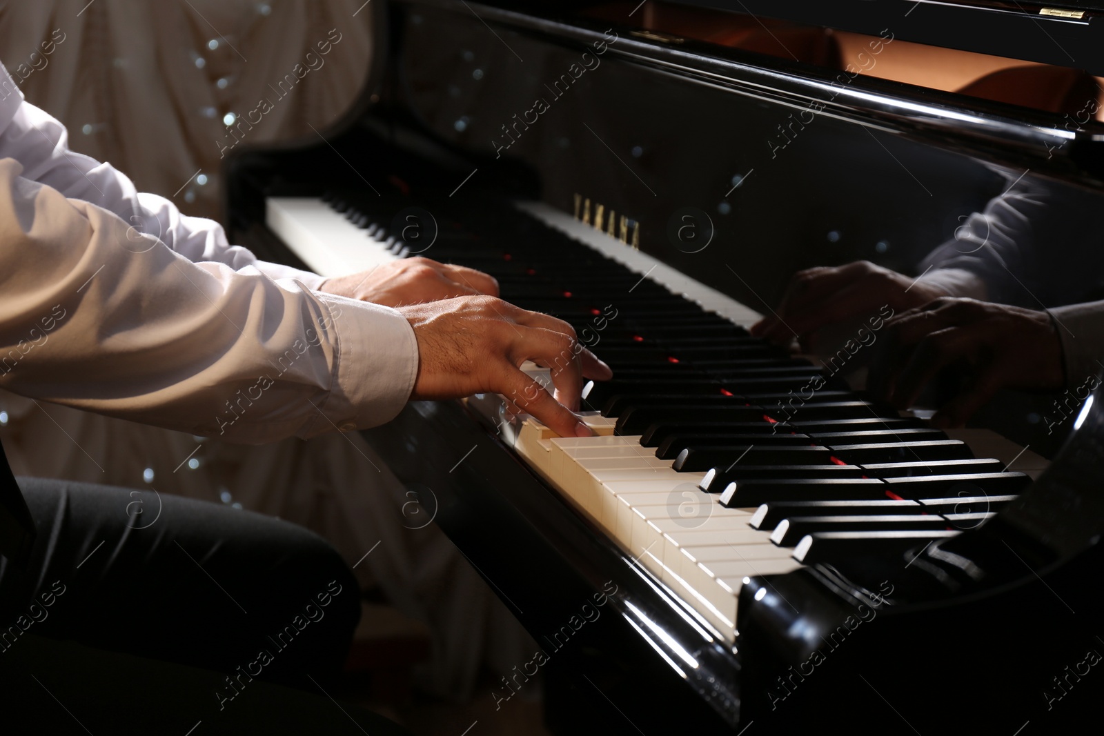 Photo of Man playing piano indoors, closeup. Talented musician