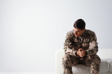 Photo of Stressed military officer sitting on sofa against white background. Space for text