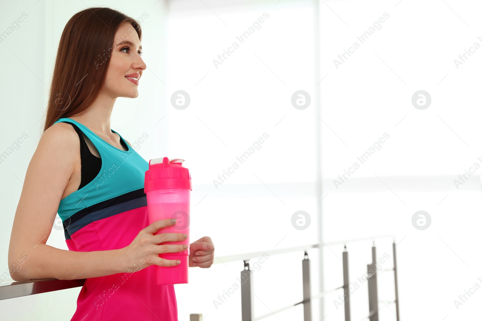 Photo of Young woman with protein shake indoors. Space for text