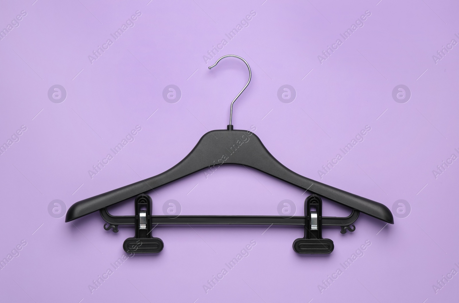 Photo of Empty hanger on lilac background, top view