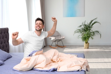 Handsome man stretching at home in morning, space for text. Bedtime