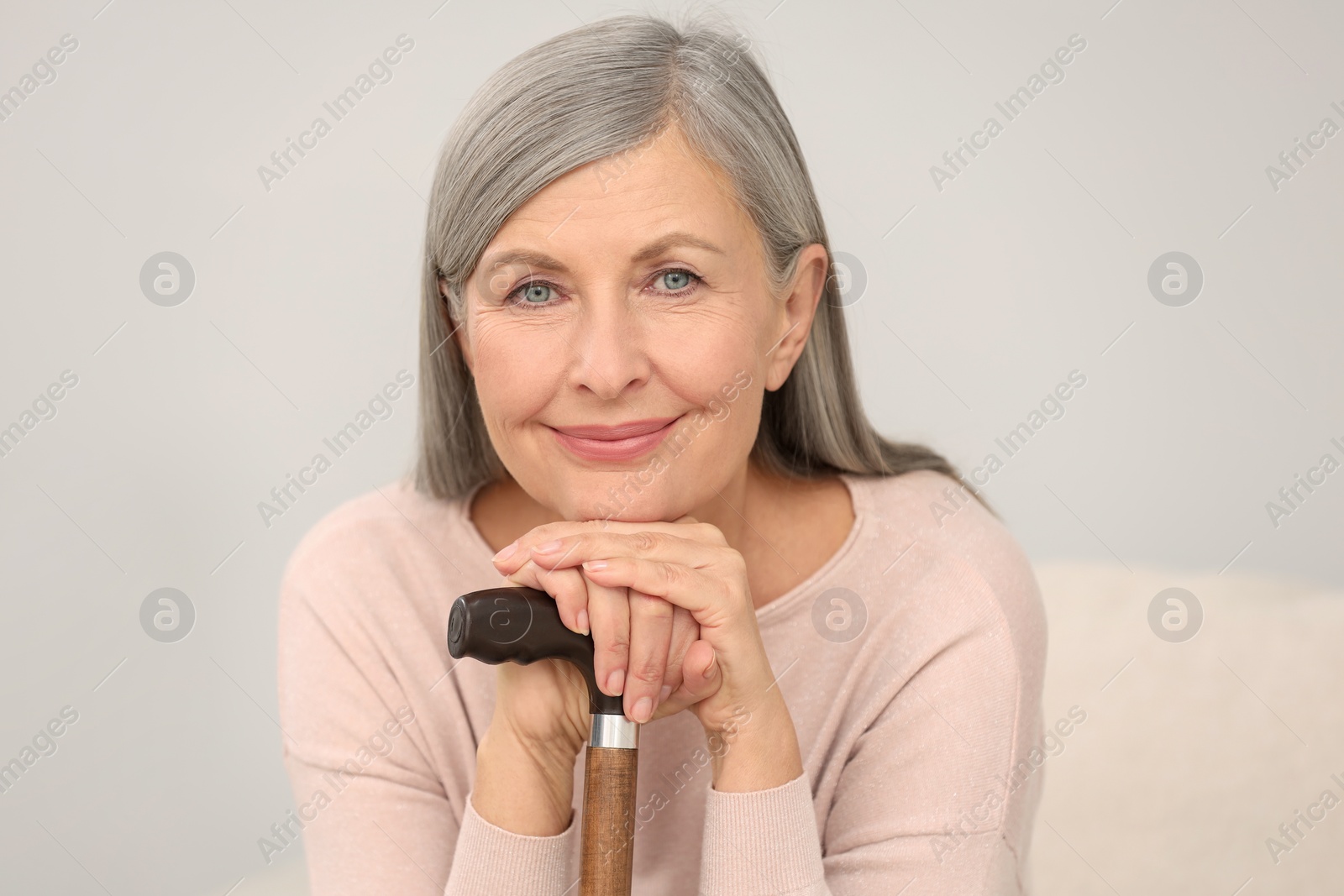 Photo of Beautiful mature woman with walking cane indoors