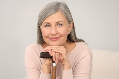 Photo of Beautiful mature woman with walking cane indoors
