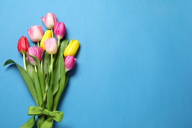 Photo of Beautiful colorful tulip flowers and ribbon on light blue background, flat lay. Space for text