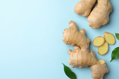 Photo of Fresh ginger with green leaves on pale light blue background, flat lay. Space for text