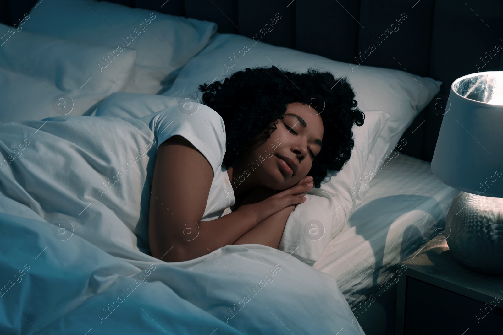 Photo of Young woman sleeping in soft bed at night