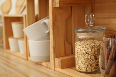 Photo of Glass jar with oat flakes on wooden shelf in kitchen