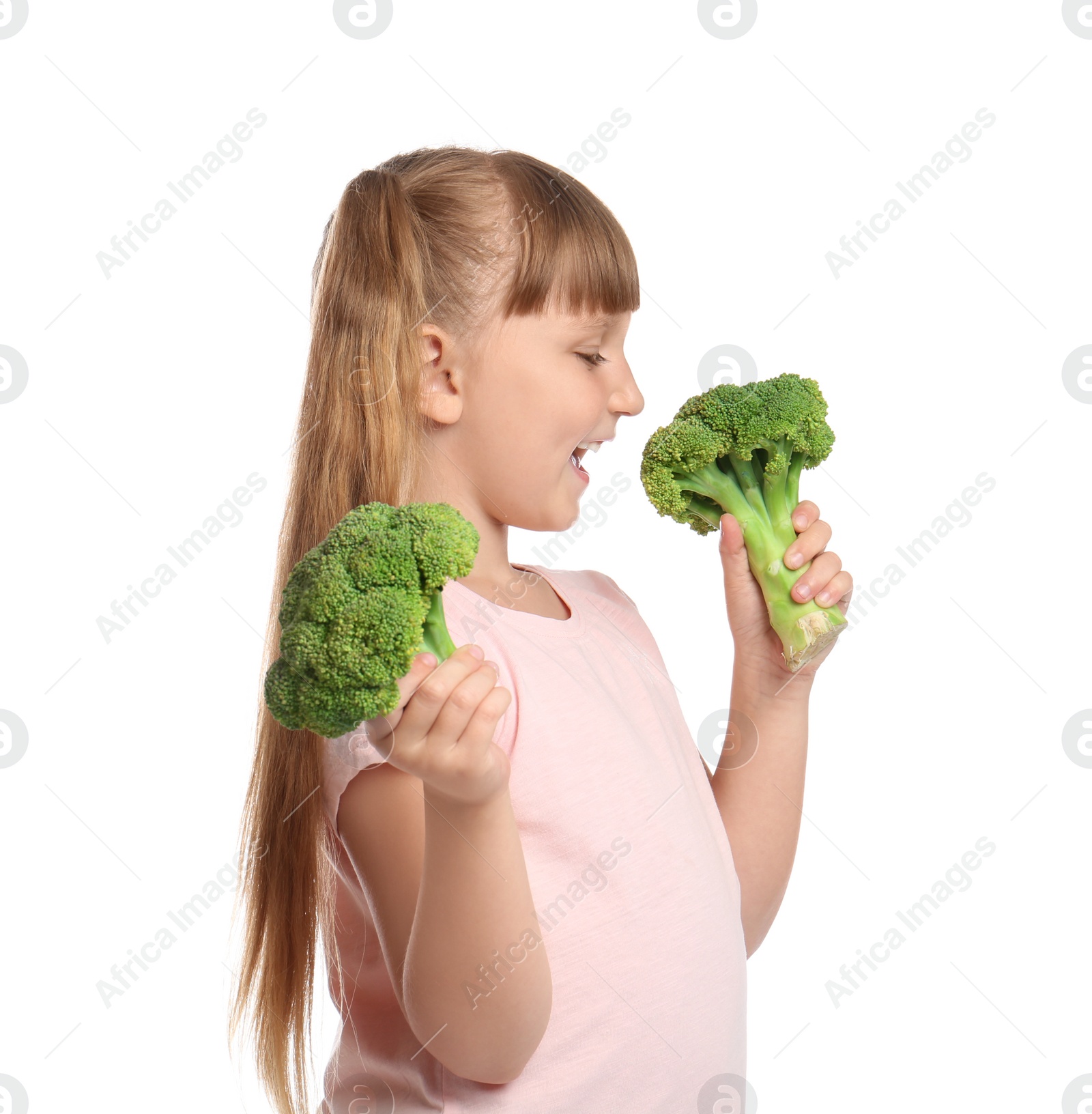 Photo of Portrait of cute little girl biting broccoli on white background