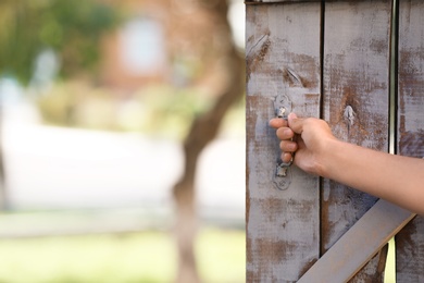 Woman opening old wooden door, closeup of hand