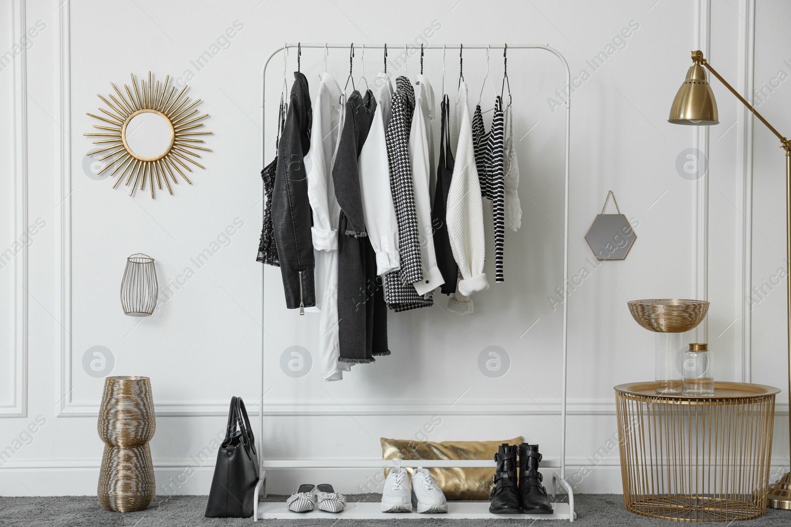 Photo of Rack with stylish clothes near white wall in dressing room