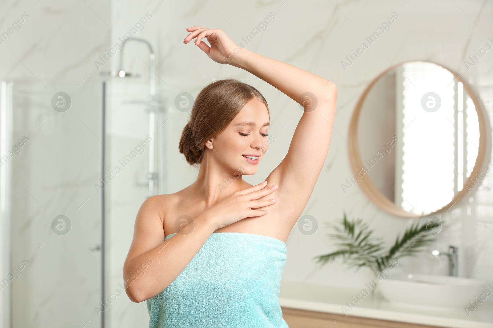 Photo of Young woman with smooth clean armpit in bathroom. Using deodorant