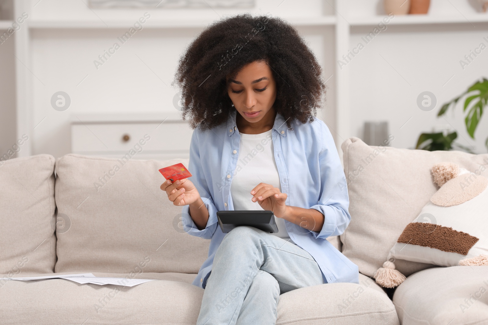 Photo of Confused woman with calculator and credit card planning budget at home. Debt problem