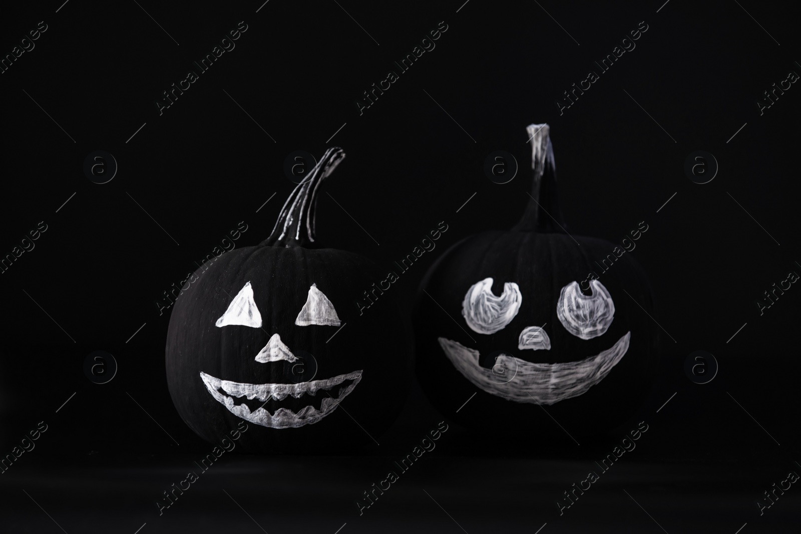 Photo of Halloween celebration. Pumpkins with drawn faces on table in darkness