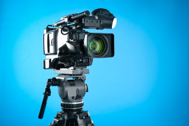 Photo of Modern professional video camera on blue background