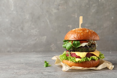 Vegan burger with beet and falafel patties on table against grey background. Space for text