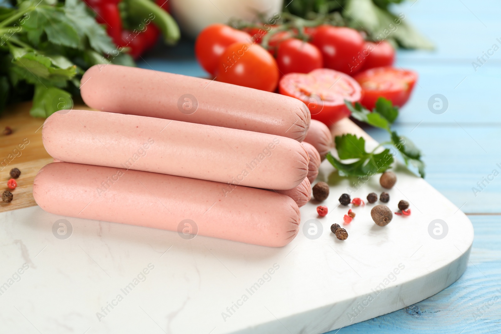 Photo of Fresh raw vegetarian sausages and vegetables on wooden board, closeup