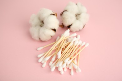 Photo of Many cotton buds and flowers on pink background, closeup