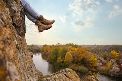 Photo of Woman wearing stylish hiking boots on steep cliff, closeup