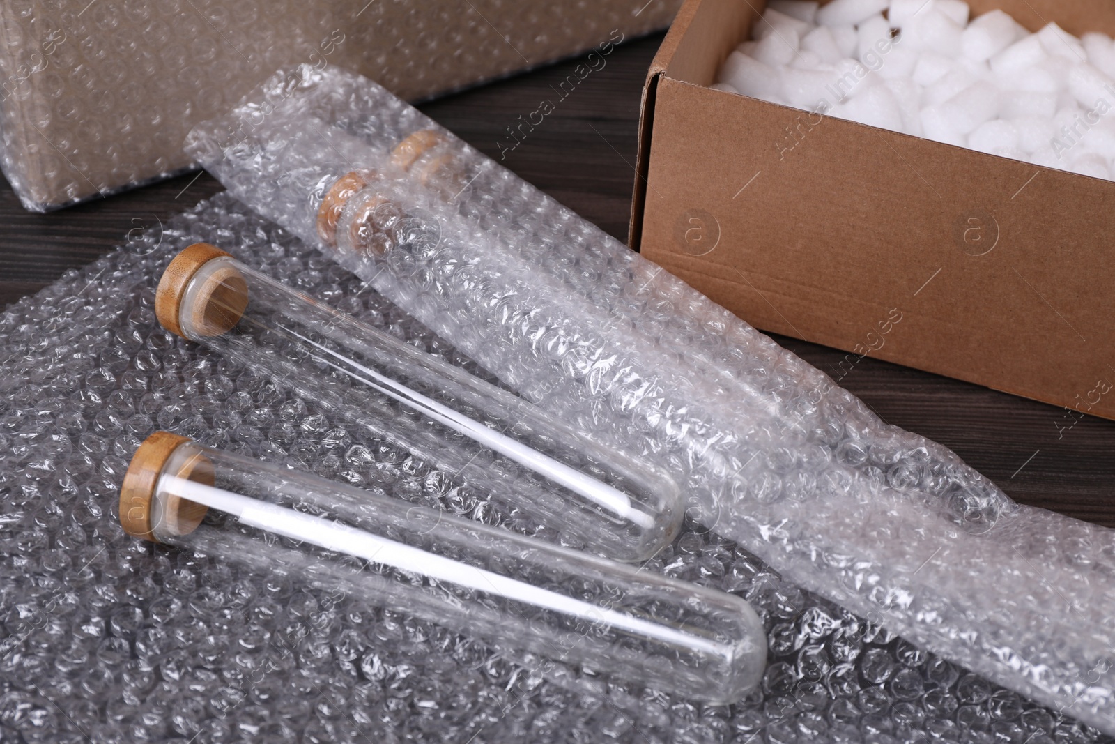 Photo of Test tubes with bubble wrap and cardboard box on table, closeup