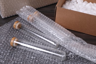 Test tubes with bubble wrap and cardboard box on table, closeup