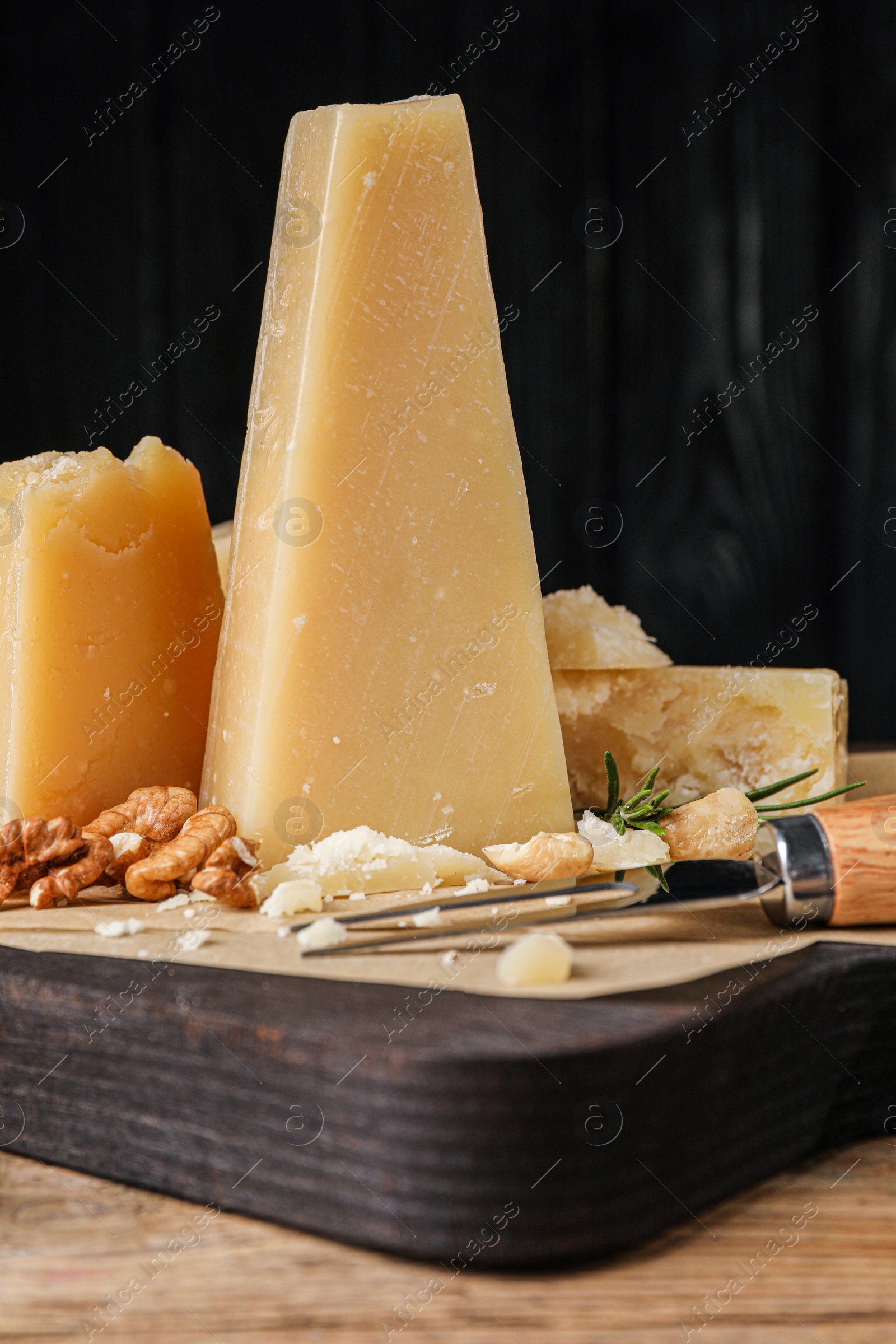 Photo of Delicious parmesan cheese with walnuts and rosemary on wooden table, closeup