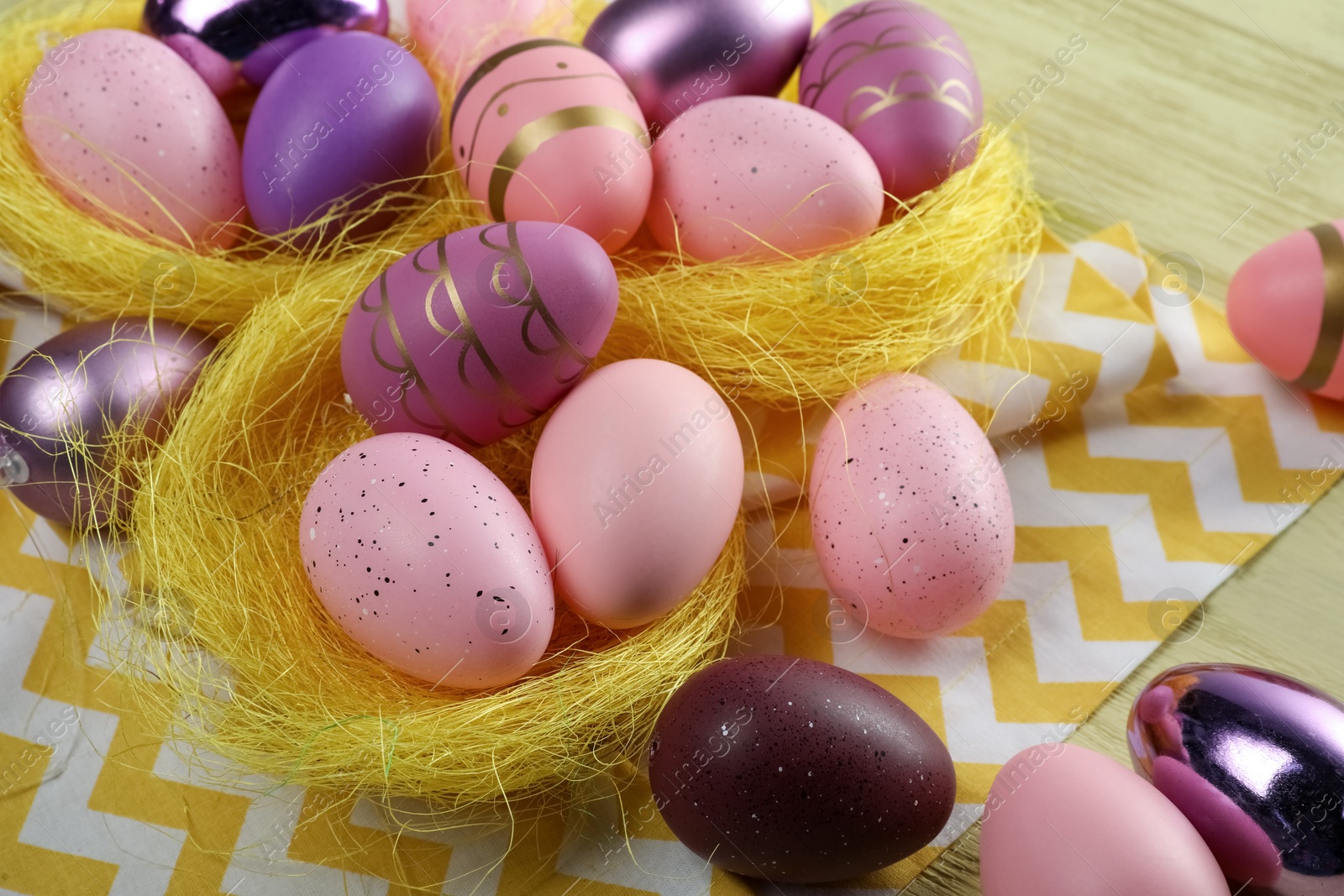 Photo of Decorative nests with many beautiful Easter eggs on table