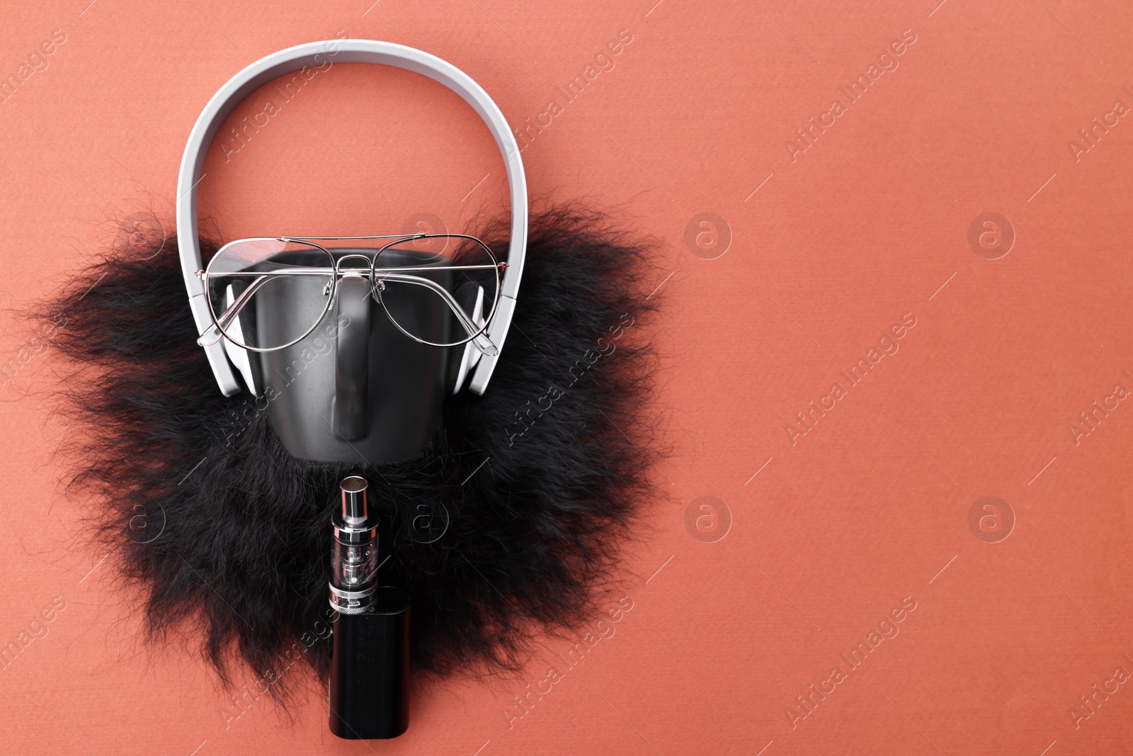 Photo of Man's face made of artificial beard, headphones and glasses on terracotta background, top view. Space for text