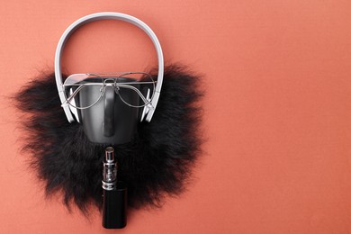 Man's face made of artificial beard, headphones and glasses on terracotta background, top view. Space for text