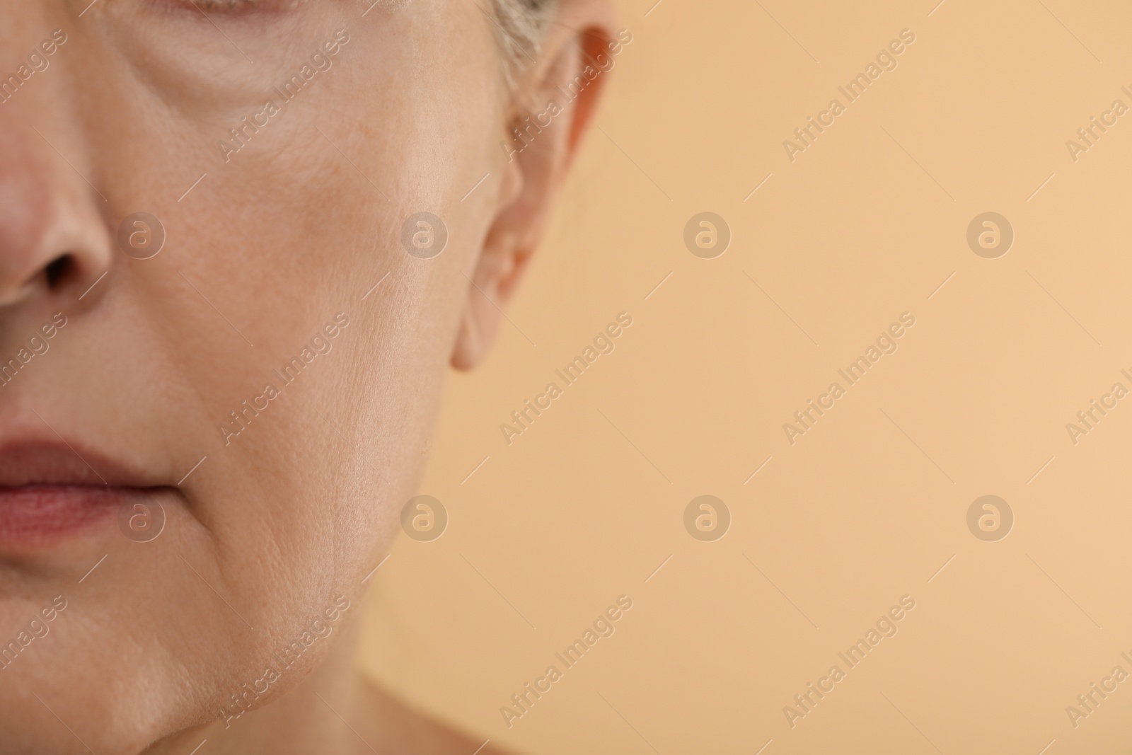 Photo of Woman with normal skin on beige background, macro view. Space for text