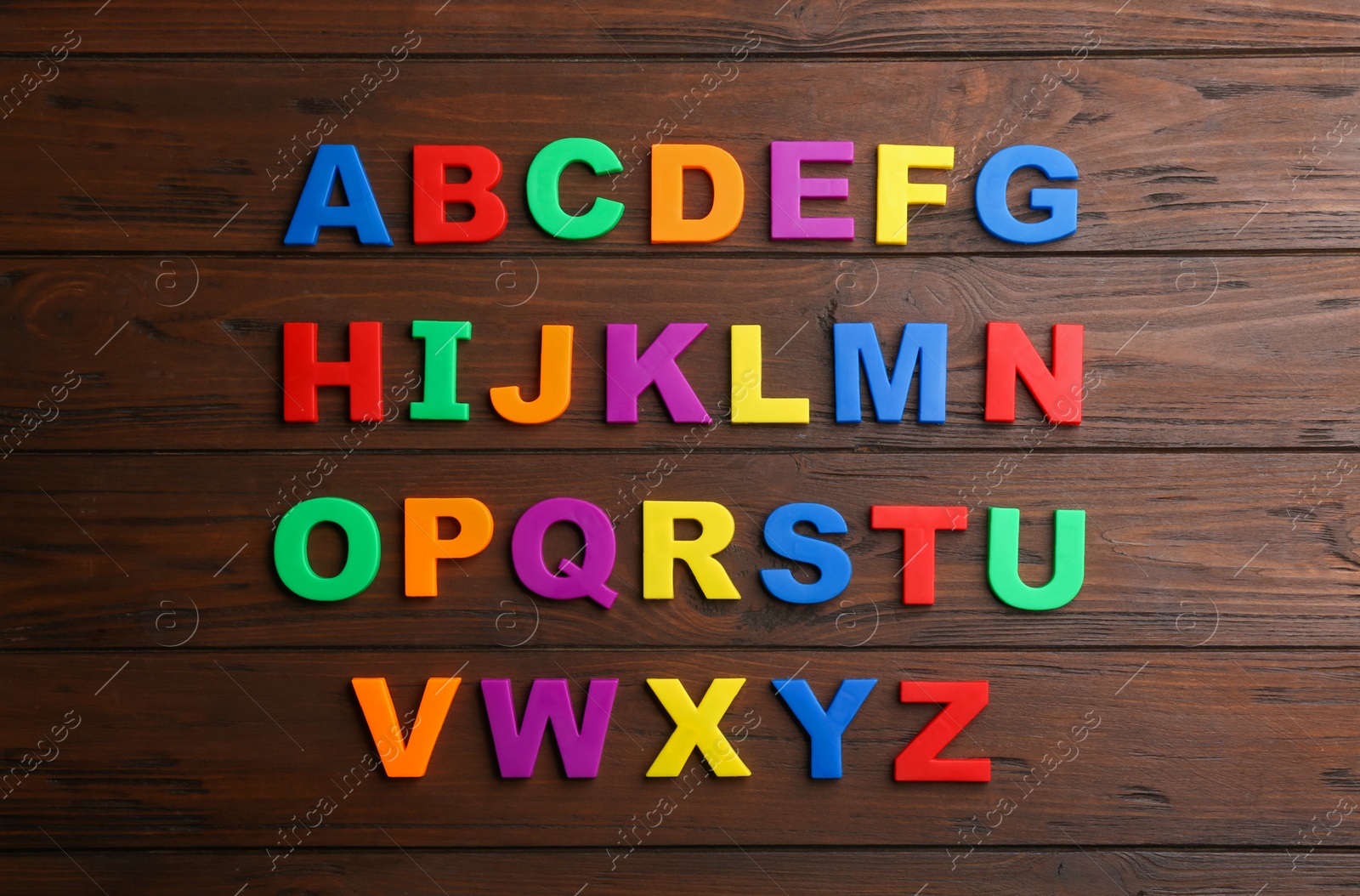 Photo of Colorful magnetic letters on wooden background, flat lay. Alphabetical order