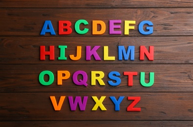 Colorful magnetic letters on wooden background, flat lay. Alphabetical order