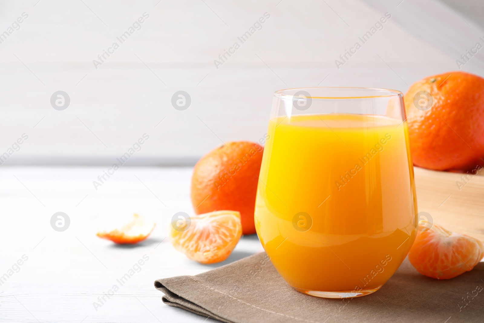 Photo of Glass of fresh tangerine juice on white table, space for text