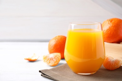 Photo of Glass of fresh tangerine juice on white table, space for text