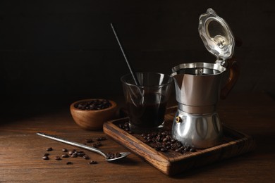 Photo of Brewed coffee, moka pot and beans on wooden table, space for text