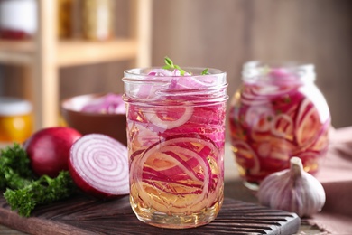 Photo of Jars of pickled onions on table indoors