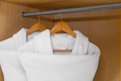 Fresh white bathrobes hanging in wooden closet