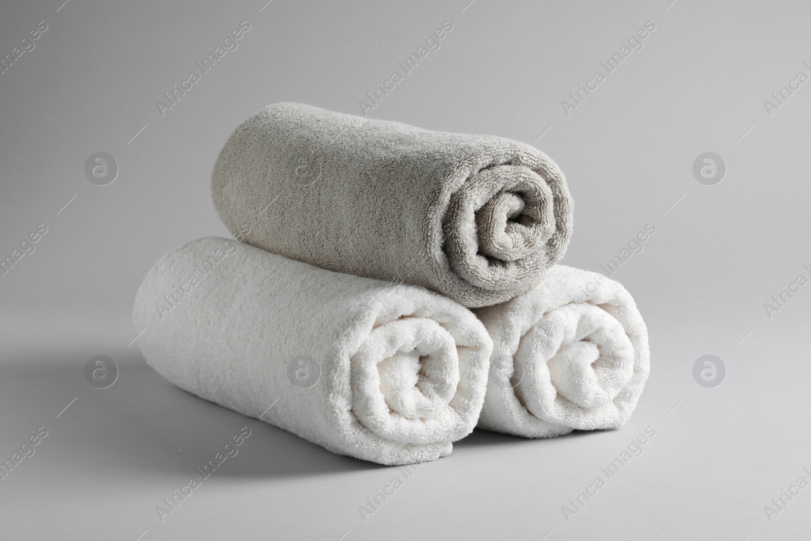 Photo of Fresh soft rolled towels on light background