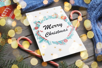 Photo of Christmas card and candy canes on grey wooden background, closeup