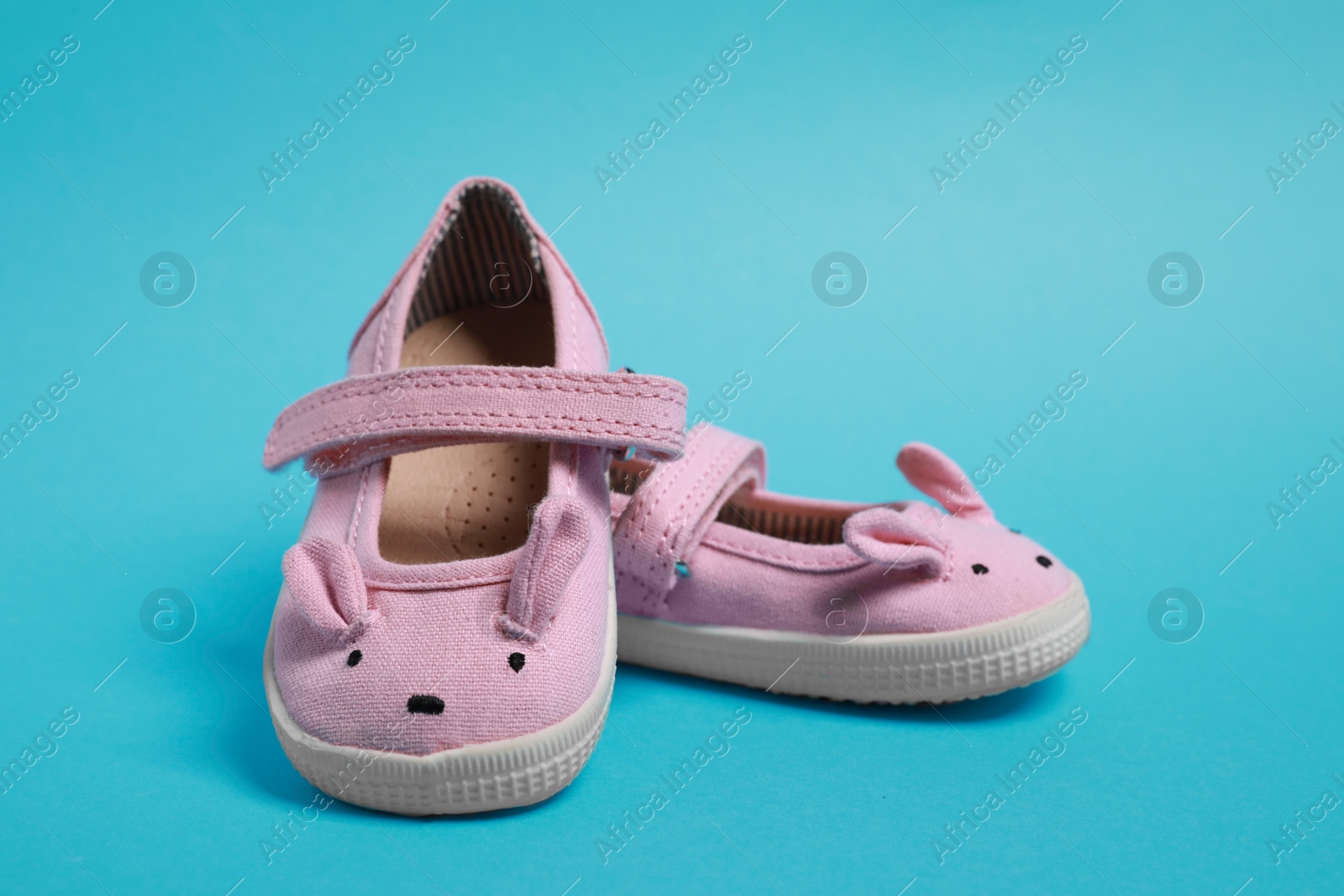 Photo of Pair of cute baby shoes on light blue background