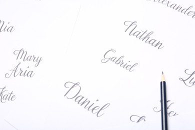 Photo of Ordinary pencil and different baby names written on paper, closeup