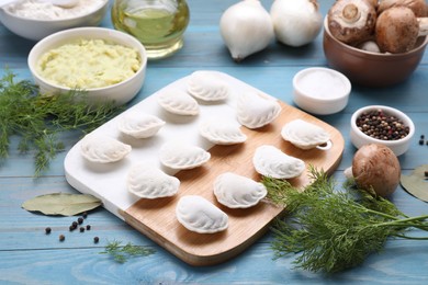 Photo of Raw dumplings (varenyky) and ingredients on light blue table