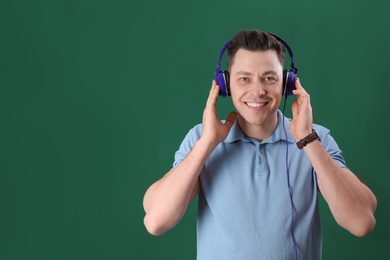 Photo of Man enjoying music in headphones on color background. Space for text