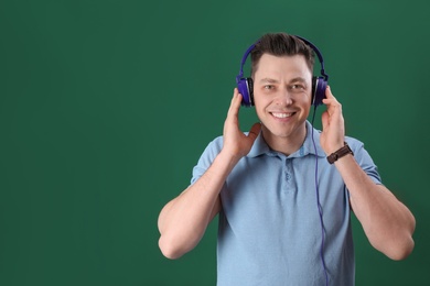 Man enjoying music in headphones on color background. Space for text