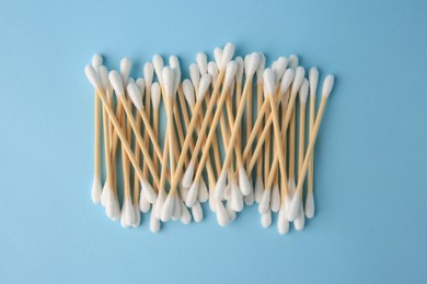 Heap of clean cotton buds on light blue background, flat lay