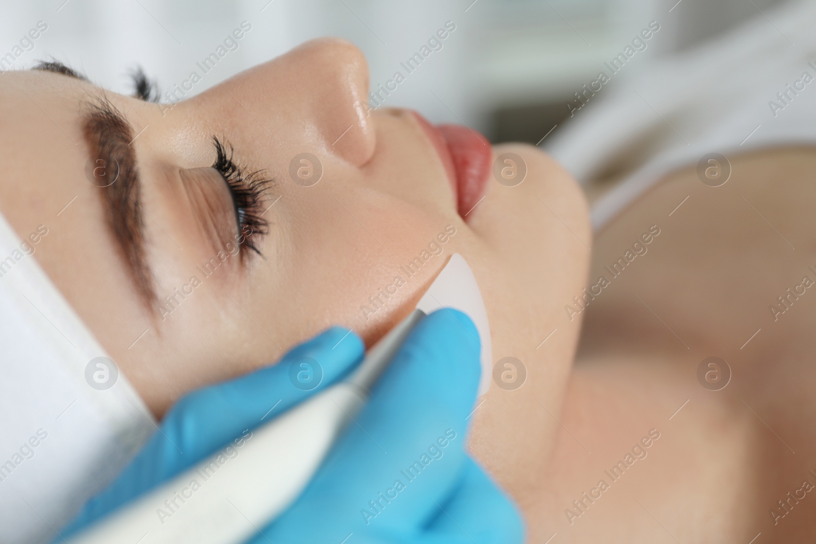 Photo of Young woman during face peeling procedure in salon, closeup