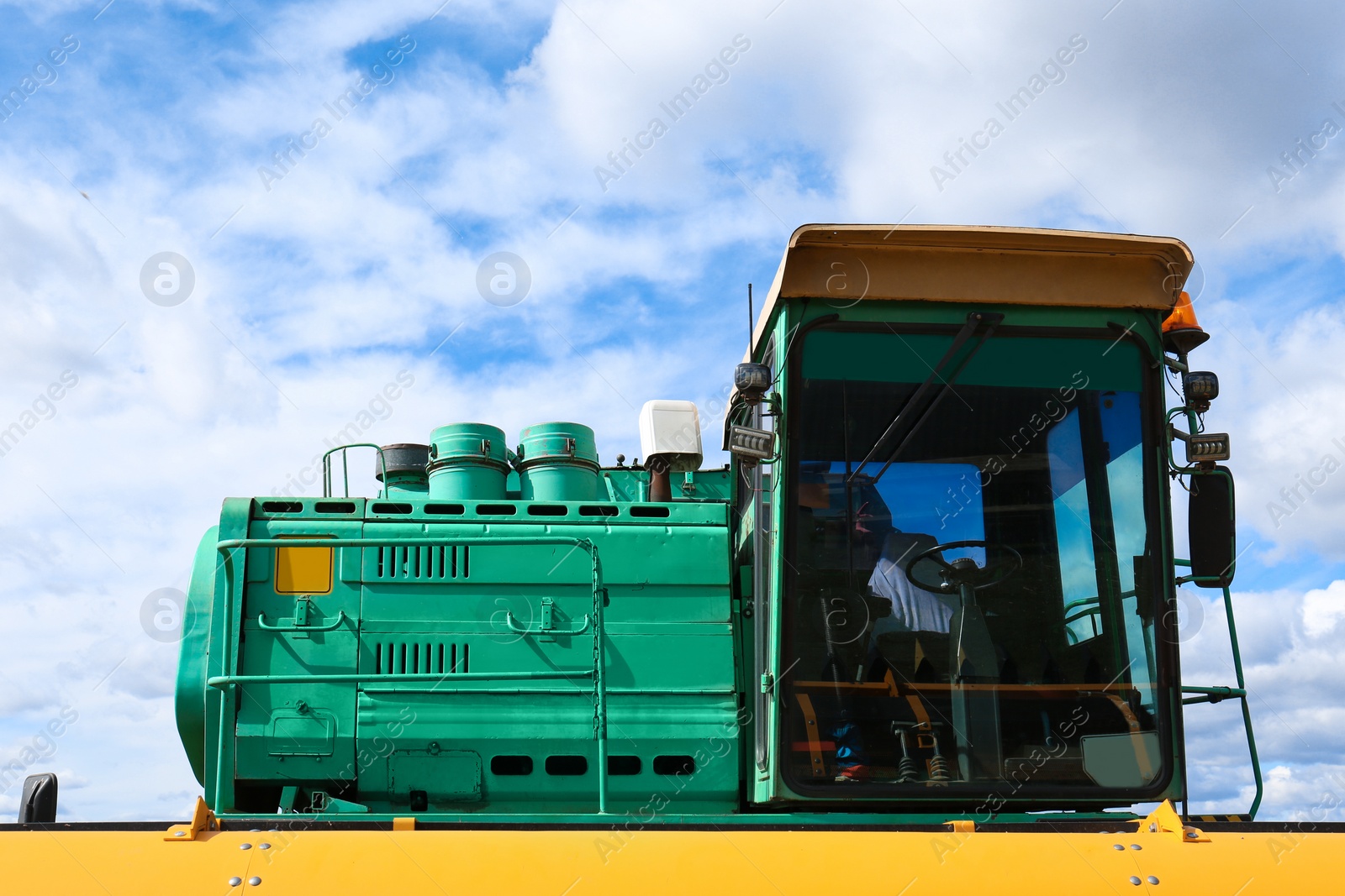 Photo of Modern combine harvester against blue sky with white clouds