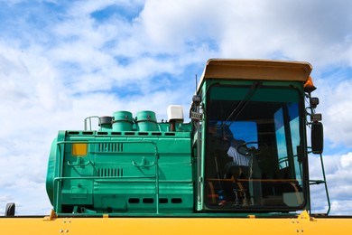 Photo of Modern combine harvester against blue sky with white clouds